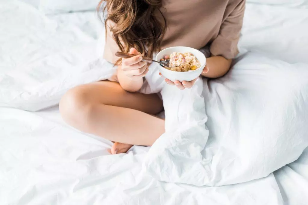 woman eating oatmeal in bed